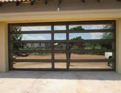 Dark aluminium sectional garage door on a paved drive